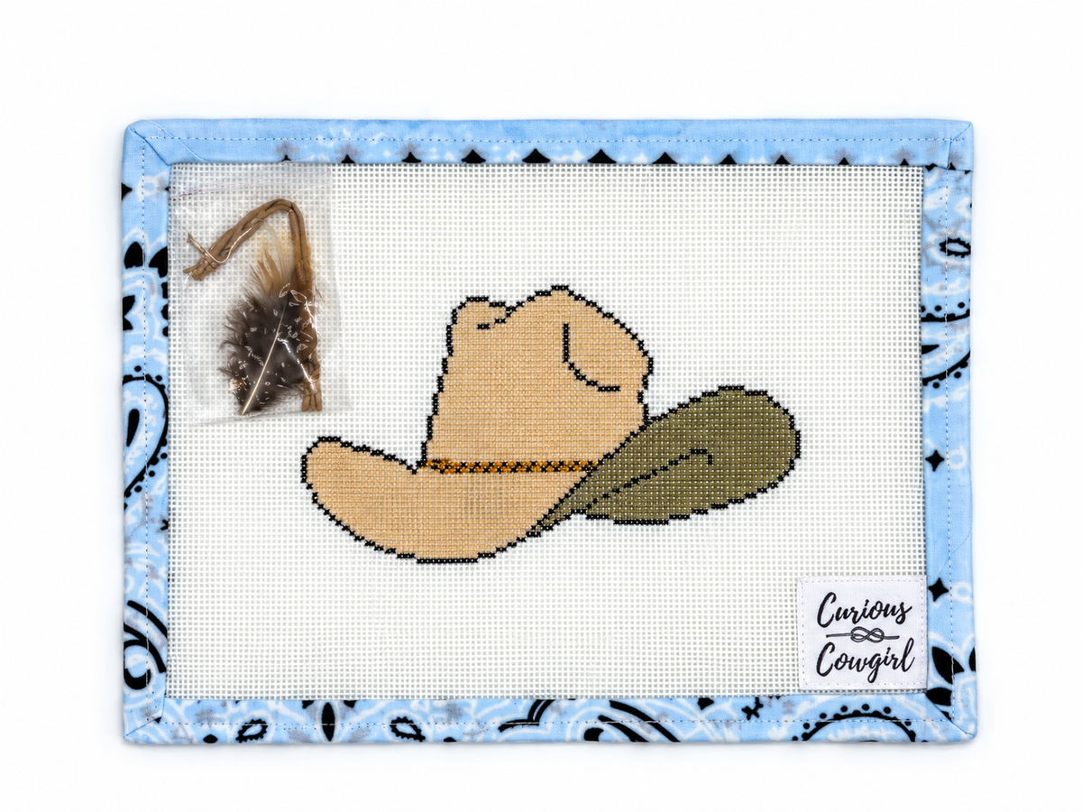 Stitch Curious Cowgirl's hand-painted Cowboy Hat needlepoint canvas, 4 x 6 inches on 18 mesh. Feather and leather cord included; threads not included.